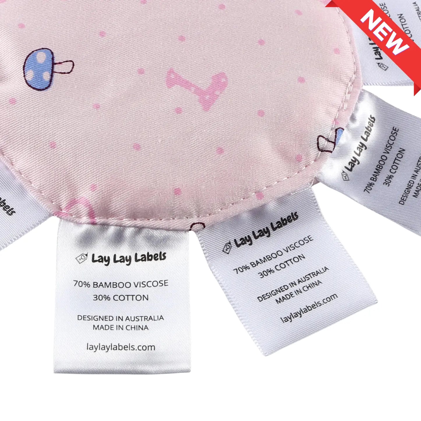 Close-up of silk and woven sensory labels on pink baby minis showing texture contrast