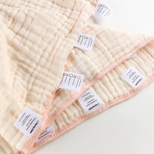 Pink baby blanket with soft fabric and textured woven labels for sensory comfort