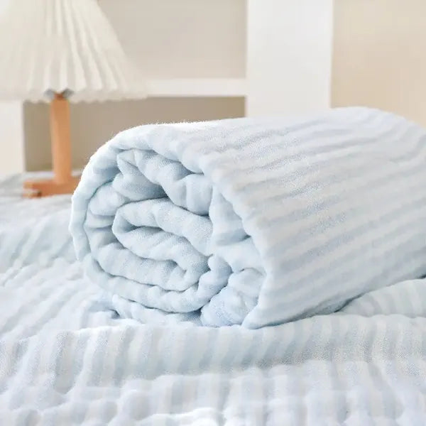 The blue blanket rolled up on a bed