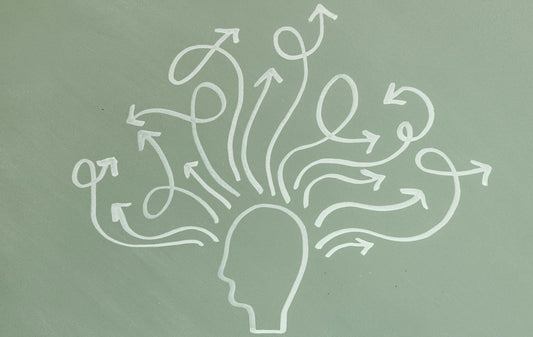 The image shows a simple chalk drawing of a head outline with many arrows swirling and branching out in different directions from it, symbolising busy thoughts, distraction, or multiple thought paths.