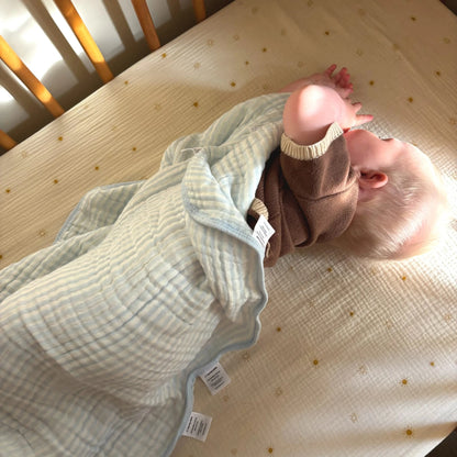 Baby lying in cot wrapped in blue sensory blanket with soft fabric and labels