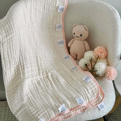 Pink baby blanket with sensory labels draped over chair in soft nursery setting