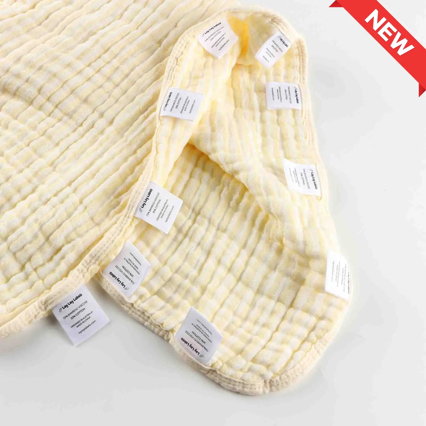 Yellow baby blanket with soft fabric and textured woven labels for sensory comfort